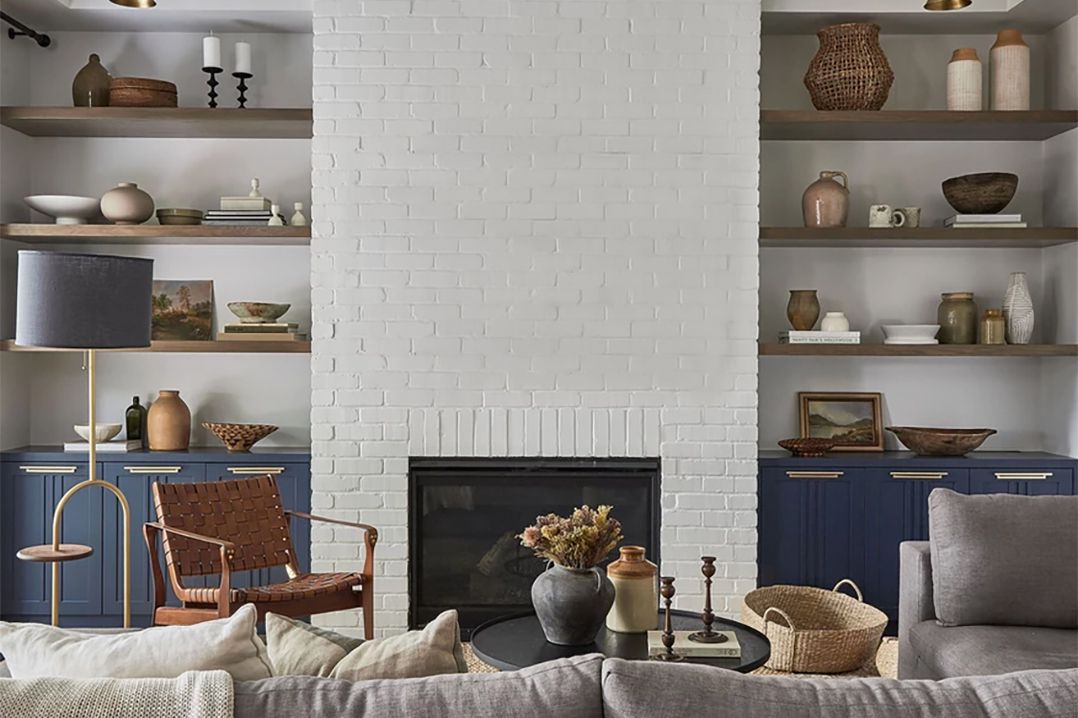 Un salon avec une cheminée en briques peintes en blanc du sol au plafond