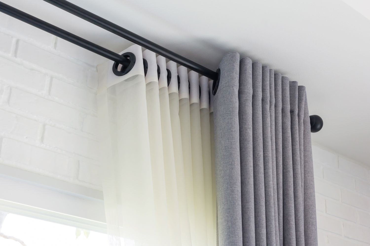 Tringle double noire avec des panneaux de rideaux transparents et gris suspendus dessus