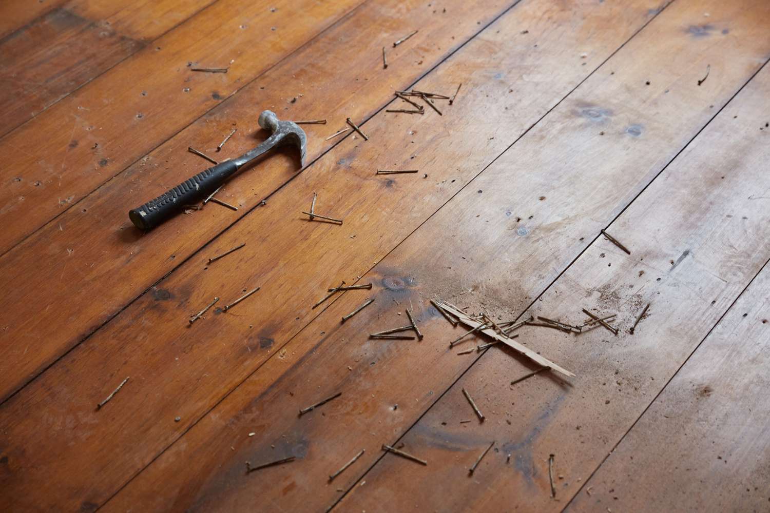 Marteau et clous éparpillés sur un plancher en bois