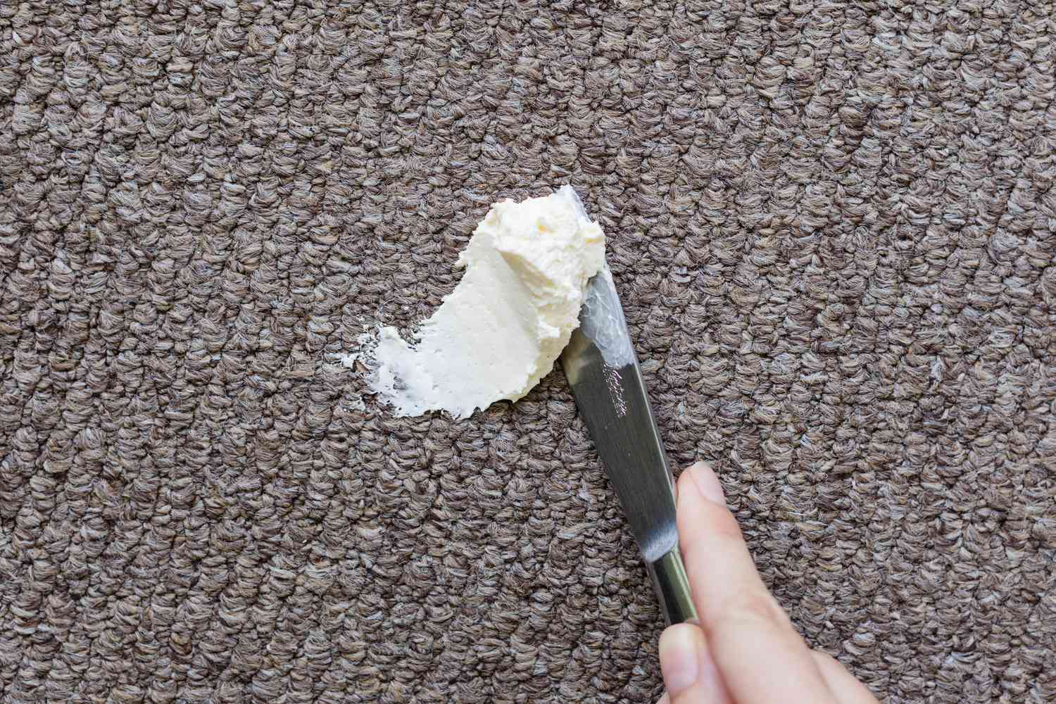 Excès de fromage à la crème enlevé du tapis avec un couteau émoussé
