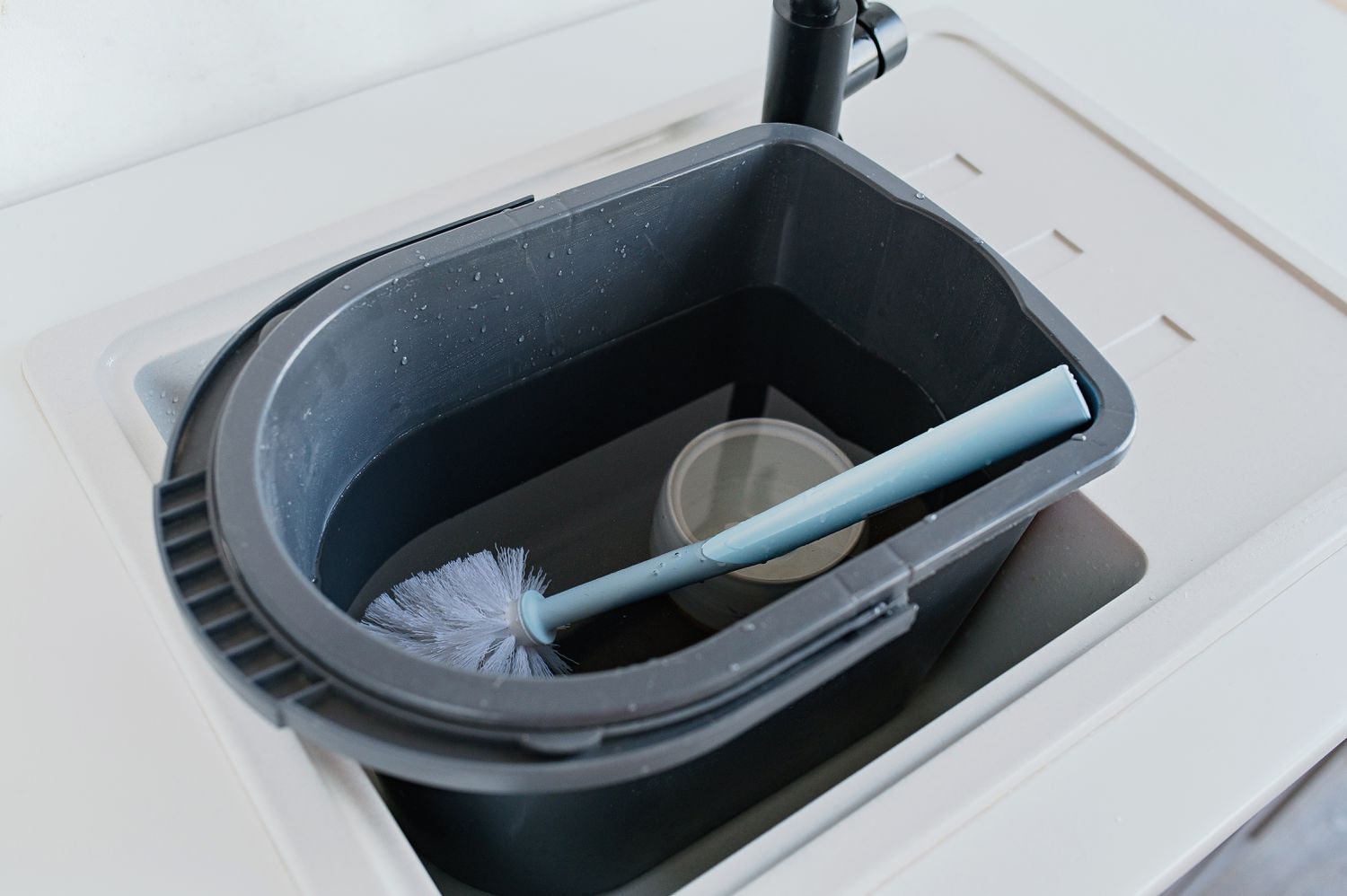 Immerger la brosse de toilette et le support dans une solution de nettoyage dans l'évier