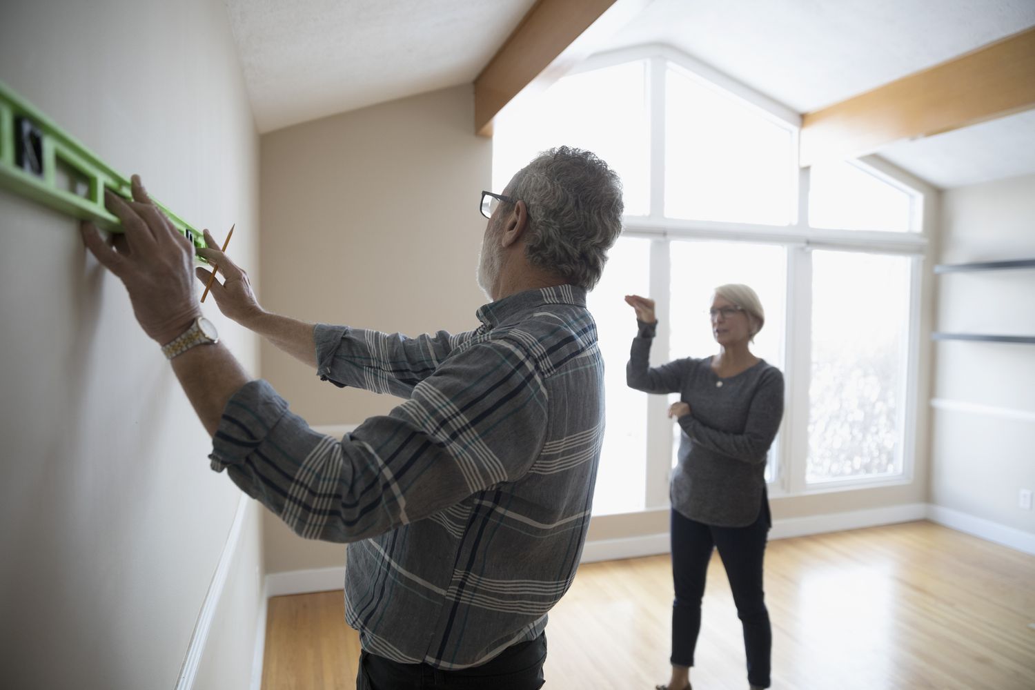 Couple de personnes âgées utilisant un outil de niveau sur le mur, se préparant à la rénovation, au bricolage