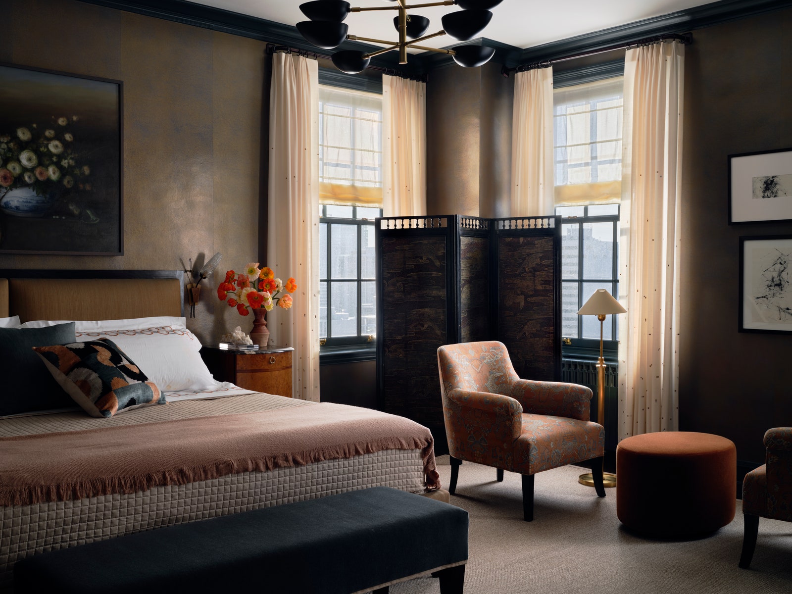 Chambre lit king size séparateur de pièce noir banc bleu petit coin salon avec deux chaises et un repose-pieds au milieu