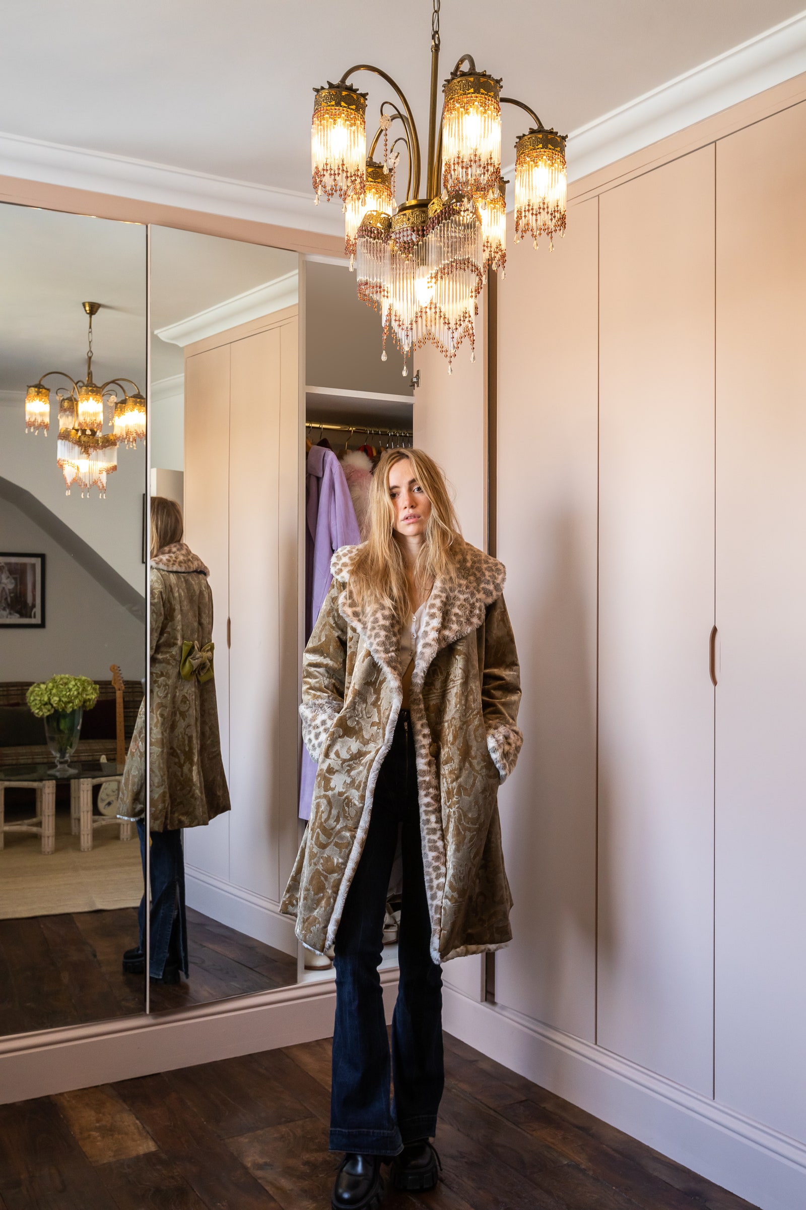 L'image peut contenir des vêtements manteau vêtements meubles personne humaine Suki Waterhouse intérieur design d'intérieur et lampe