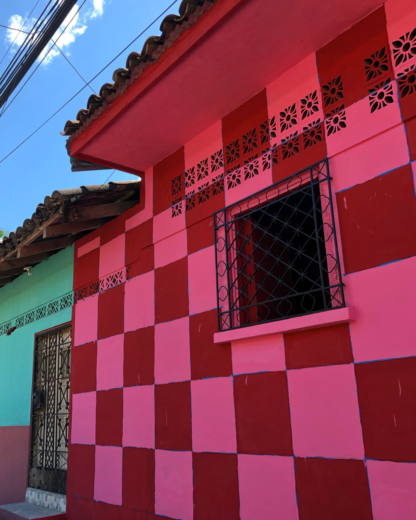Une maison à carreaux rose vif et rouge dans la ville natale des parents des auteurs à l'extérieur de San Miguel El Salvador.